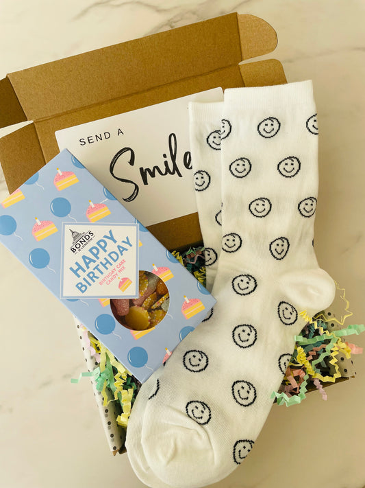 colorful birthday gift box featuring a selection of pick n mix sweets and fun smiley face socks, perfect for celebrating a special day. 