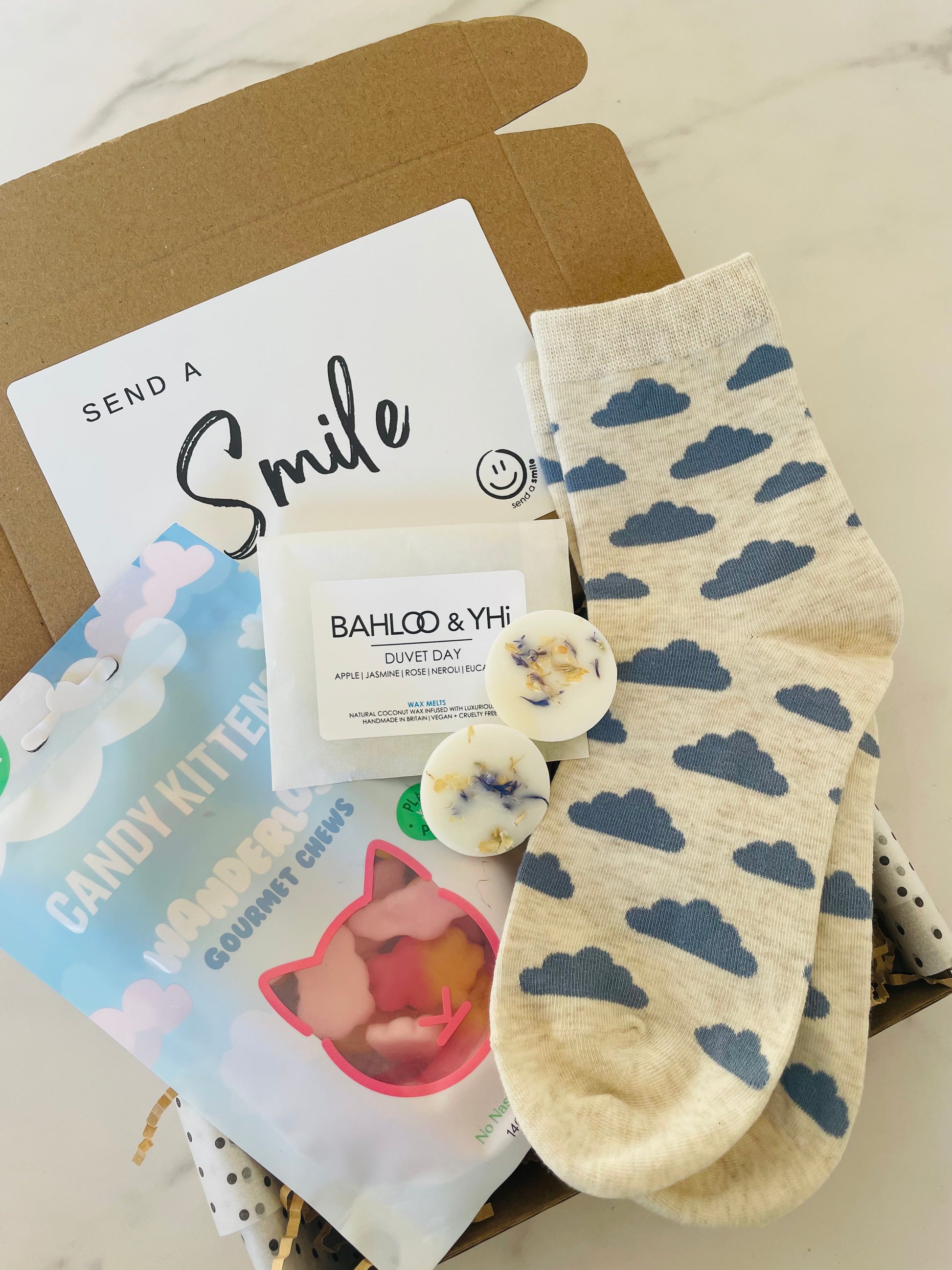 A Cloud Nine Gift Box featuring candy kitten sweets, dreamy cloud socks and botanical wax melts.