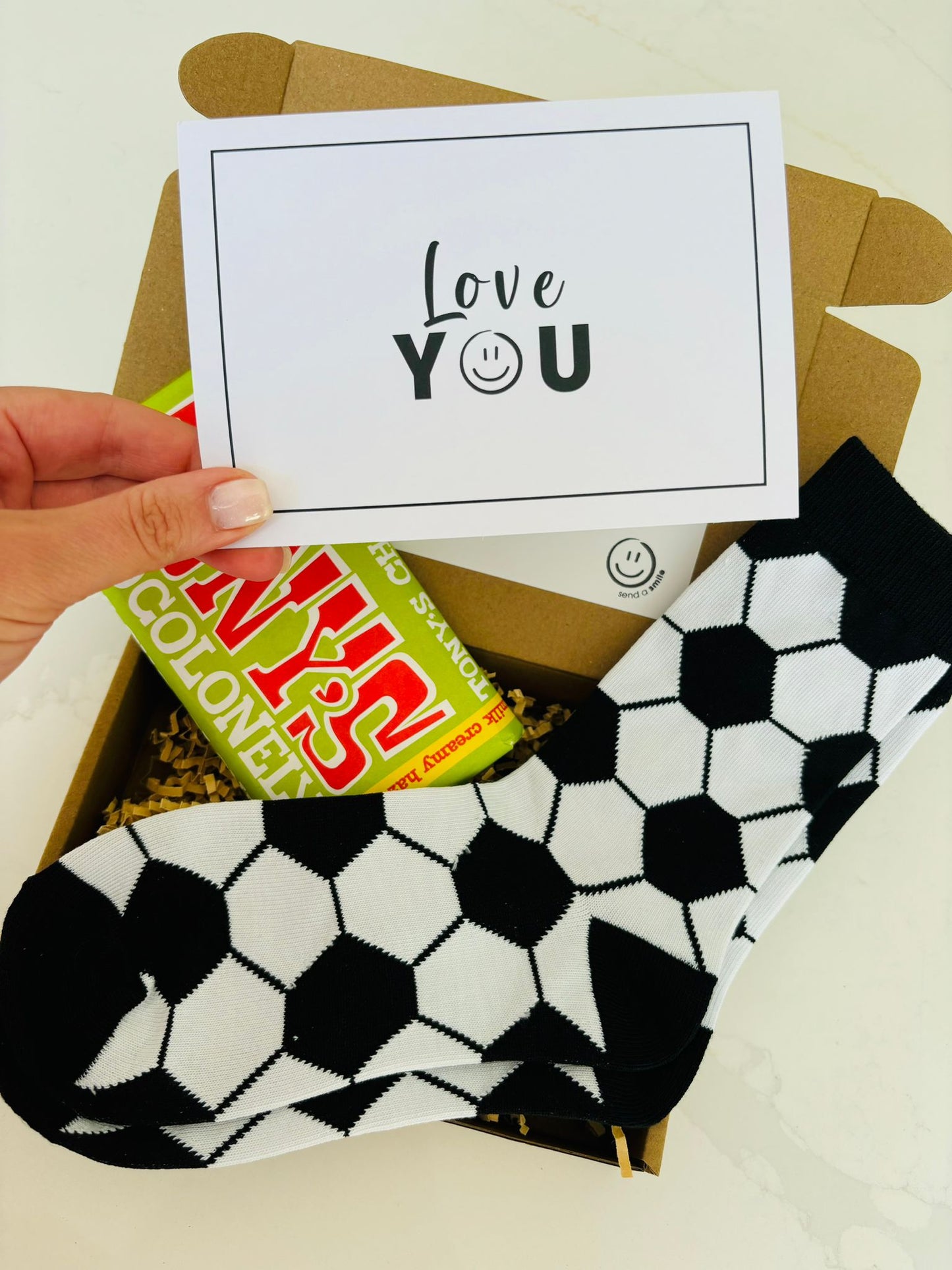 A football-themed gift box containing football socks, a card that reads "Love You", and Tony's Chocolonely. 