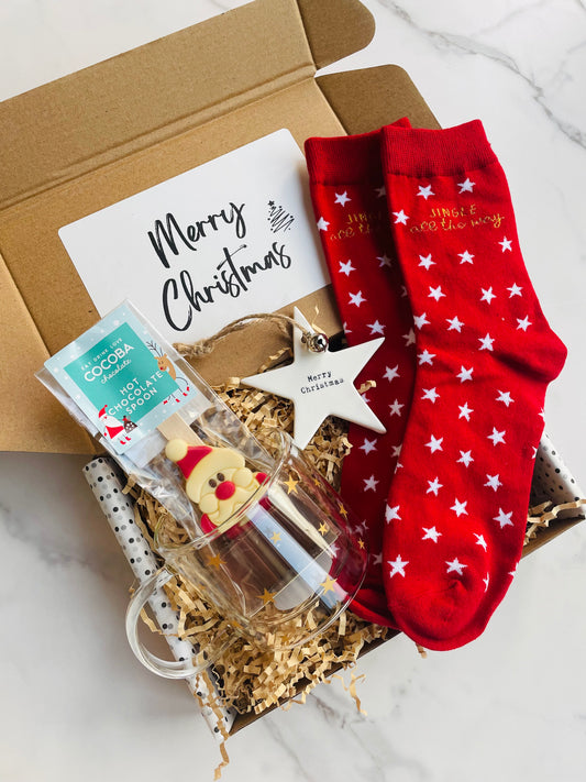 Christmas gift box containing Glass mug with gold stars, Santa hot chocolate spoon, embossed 'Merry Christmas' star decoration, red socks with white stars 'Jingle all the way' 