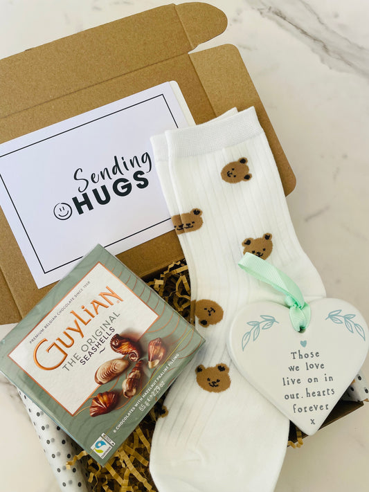 A beautifully wrapped gift box with a postcard that reads "Sending Hugs" symbolizing warmth and affection. 