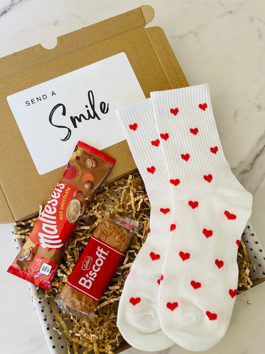 A delightful gift box featuring red heart socks, Biscoff biscuits, and Maltesers hot chocolate, ideal for a thoughtful present. 